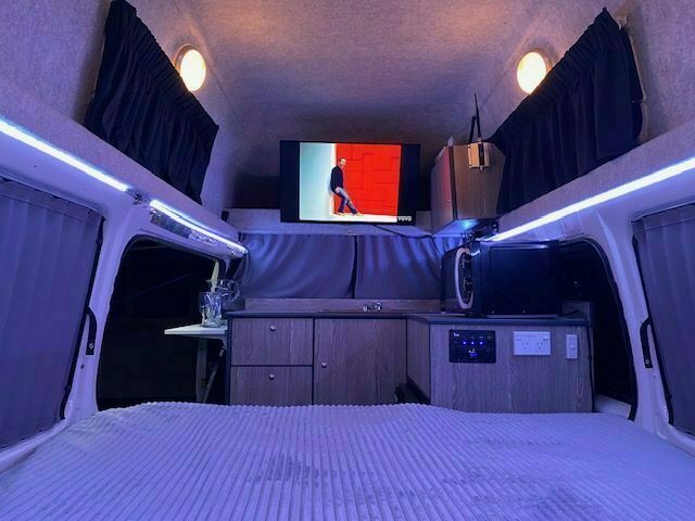 Campervan bed made up in the evening with the smart TV on and LED mood lighting