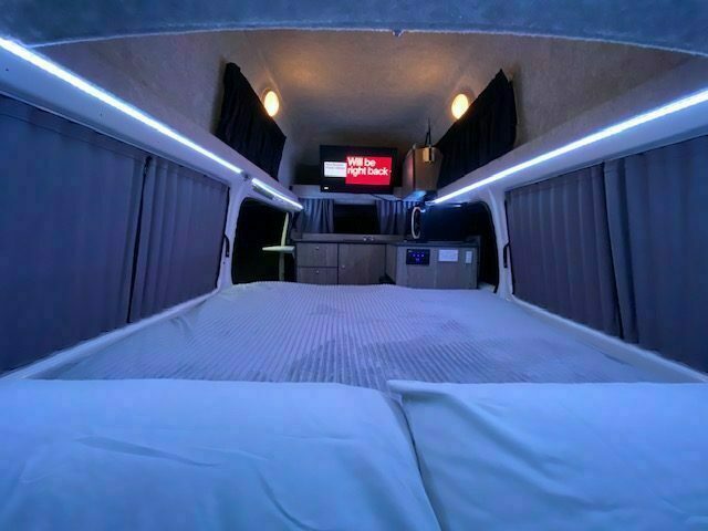 Inside the campervan looking to the rear bed with mood lighting and a smart TV