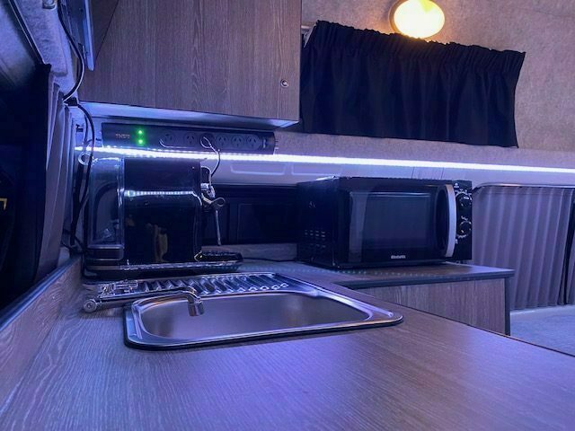 Campervan kitchen with gas hob, sink, microwave and bench space