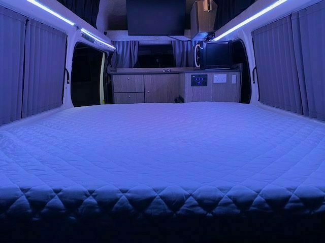 Made-up queen bed inside the Toyota Hiace campervan