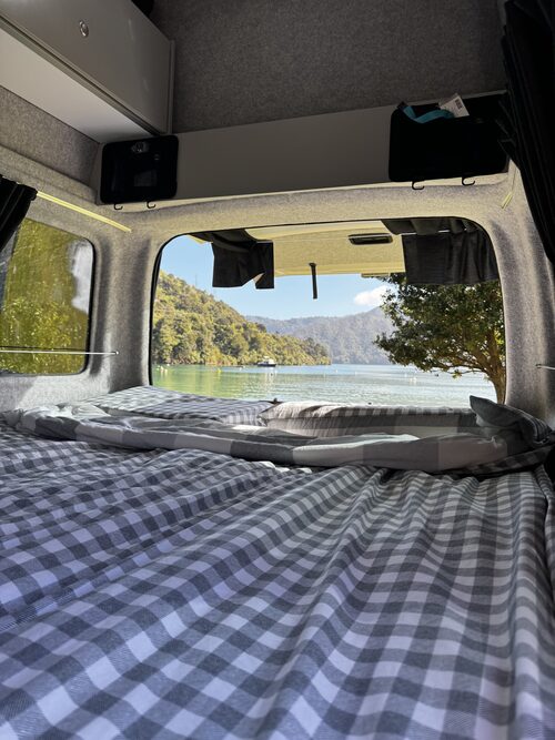 The double bed made up inside Harriet with the rear doors open to a lake view