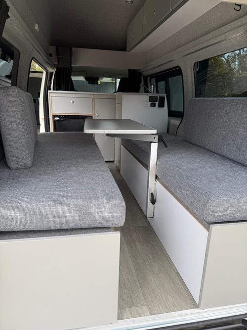 Two facing bench seats and the fold-away table inside Harriet, which convert into the double bed